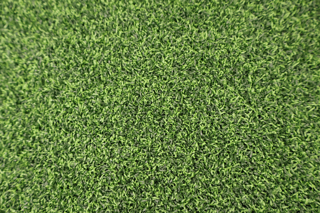 Green artificial turf texture with dense short grass blades filling the frame.